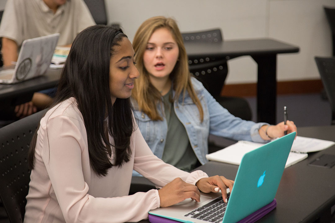 Two CCAS students working at a laptop together
