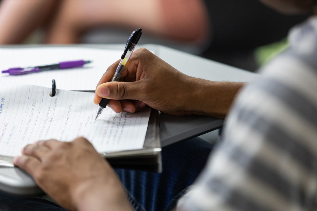A person's hands shown writing in a notebook