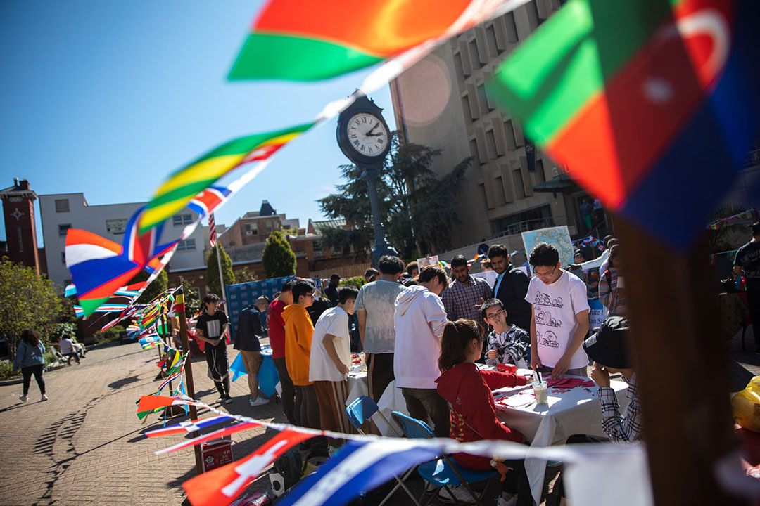 Students at a GW International Students Office event in Kogan Plaza with country flags waving in the wind.